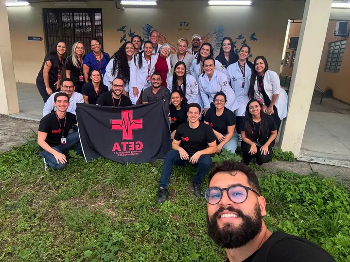 Turma do GETA reunida ao ar livre com a bandeira do grupo